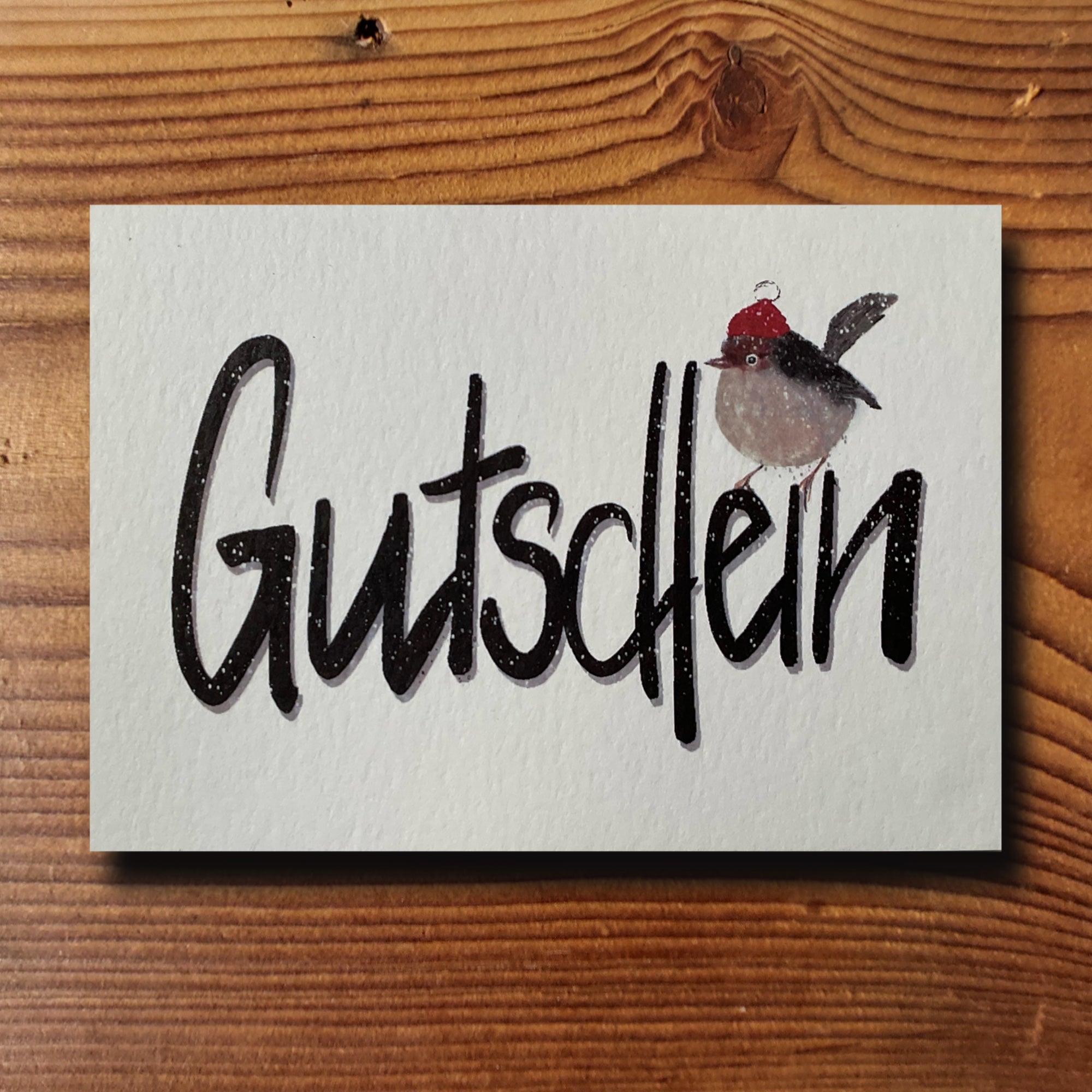 Gutscheinkarte mit handgezeichnetem Lettering-Schriftzug Gutschein und Rotkehlchen mit Weihnachtsmütze, naturweiss A6, von KicomiArt