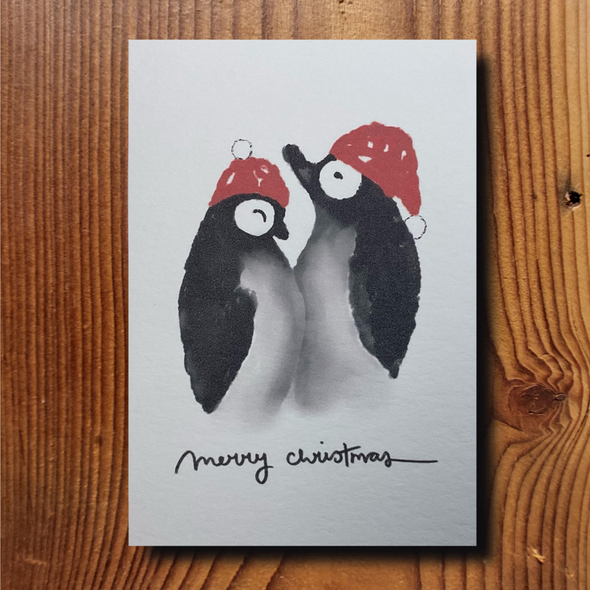 Weihnachtskarte mit zwei Pinguinen in Weihnachtsmützen und Schriftzug Merry Christmas, naturweiss A6, von KicomiArt